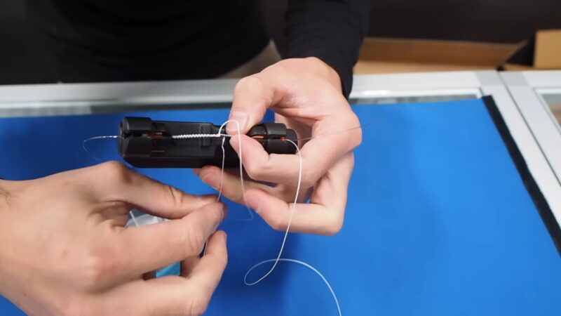 Person using electric fishing knot tying tool to make a knot